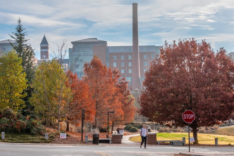 A student walks across the intersection between the Scroll of Honor Memorial and Death Valley amid bright fall foliage.