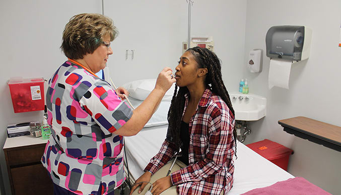 A nurse takes the temperature of a female student in a medical facility on Clemson's campus.