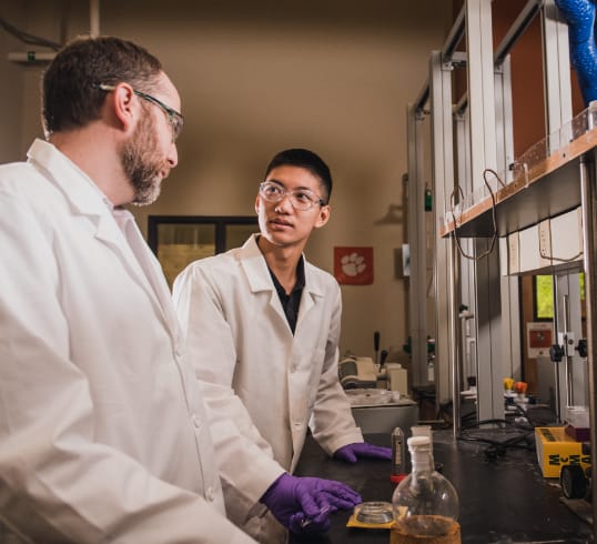 Faculty advisor and male student work together in a science lab.