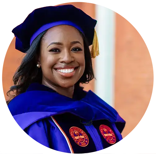 A female doctoral student wears academic regalia, including a purple gown, dark purple velvet graduation cap and dark purple stole with an orange Clemson University seal mark. 