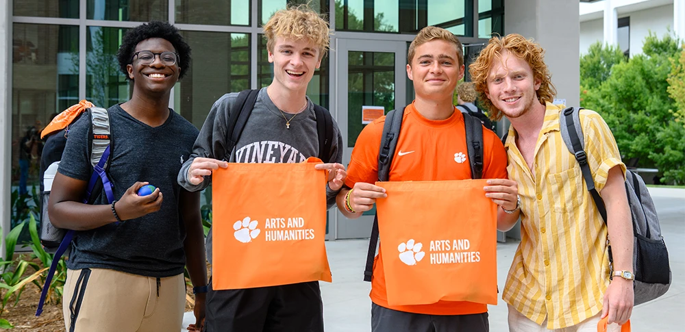 A first-year class of students wearing orange T-shirt gathers on the field of Memorial Stadium to form the shape of the Clemson Tiger Paw.