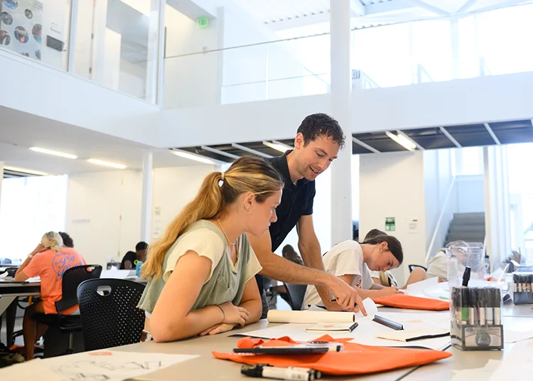 a male faculty member instructs a summer scholar student at a table in the architecure building