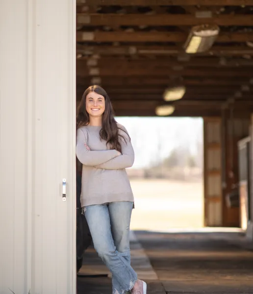 A female student wears a gray sweater and denim jeans.