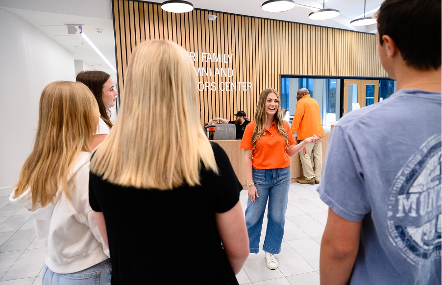 A female student tour guide speaks with three female students and a male student inside the Nieri Family Alumni and Visitors Center.