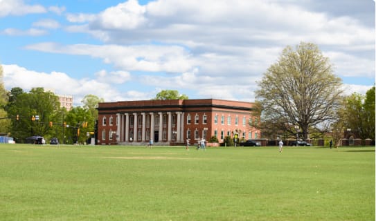 A green lawn and a brick administrative building with columns.