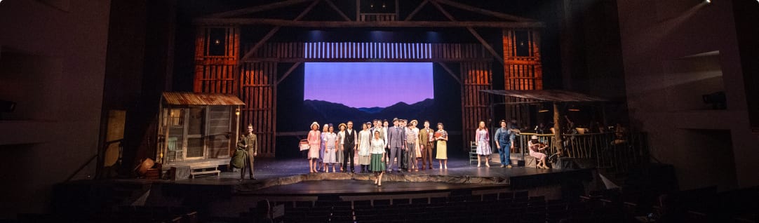 A group of actors stands on a stage during a theater performance.