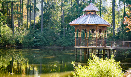 A gazebo overlooks a pond and trees.