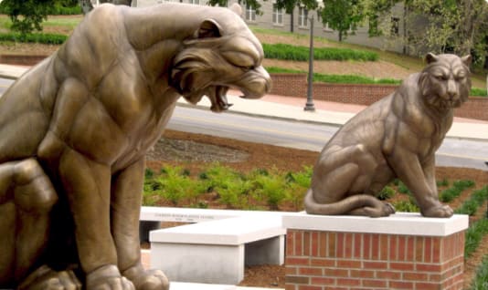 Two bronze statues of tigers sit atop brick pedestals.