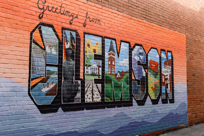 A mural in the style of a vintage postcard says, 'Greetings from Clemson.'